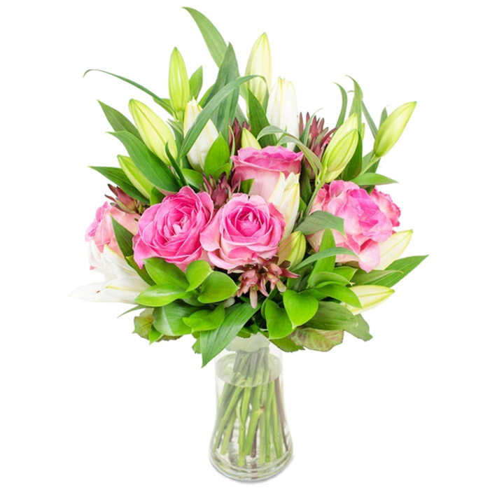 A lush, full bouquet of deep pink roses and crisp white lily buds is presented in a clear glass vase, the arrangement isolated on a bright white background so every nuance of colour and texture reads clearly. The focal roses are large and fully blossomed, petals layered in tones from pale blush at the outer edges to intense fuchsia toward their centers, creating a soft, tactile sweep that invites touch. Between and above these, white lily buds stand tall and sculptural; many remain closed with gentle green tips, while a few are beginning to open into trumpet-shaped blossoms, offering a hint of powdery white fragrance. Around the blooms, a generous assortment of foliage - glossy broad leaves, smaller rounded greens, and light, airy sprigs - creates depth and volume, shaping a rounded silhouette that sits comfortably on a mantel or dining table. Darker reddish-brown or burgundy accent buds are woven through the greens, introducing small pockets of contrast that give the bouquet a carefully composed, lived-in quality. The glass vase shows clear water and cleanly cut green stems, its flared rim and simple profile underscoring the arrangement's timeless elegance. The overall impression is one of freshness and expert craft, the kind of bouquet a Brent Cross resident might select for an anniversary, a new home near Staples Corner or Golders Green, or to lift a friend's spirits after a long week. The presentation suggests skilled handling and reliable freshness for local delivery across Brent Cross and neighbouring streets like Cricklewood Broadway.