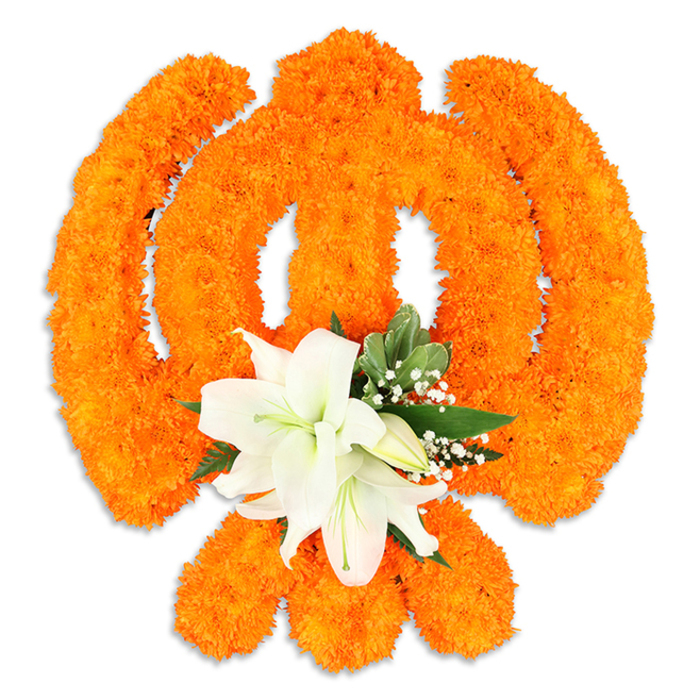A meticulously arranged Ik Onkar symbol unfolds across a pristine white background, its form entirely composed of thousands of small, bright orange marigold blossoms whose clustered heads create a rich, textured surface. The distinctive strokes of the Ek Onkar - the vertical Ek and the curved flourishes that follow - are carefully modelled by the marigolds' round, compact faces, producing clear negative spaces and a softly sculpted edge that reads like calligraphy rendered in bloom. At the lower central area, a graceful cluster of white lilies provides a luminous focal point: two or more open lilies with gently arching petals reveal subtle green and yellow stamens, while surrounding buds promise evolving form. Interspersed among the lilies are delicate sprays of tiny white filler flowers and fresh green leaves, their varied textures and tones adding a quiet softness to the bold orange palette. The overall composition casts a faint drop shadow, giving the symbol a tangible, three-dimensional presence as if poised for placement at a gurdwara doorway or a community ceremony. The contrast between the warm marigolds and the cool white lilies evokes both celebration and serenity; the scent balance is of bright, citrus-marigold note tempered by the mellow sweetness of lily. As a floral statement this Ik Onkar conveys devotion, unity and the simple declaration God is One, and would be appropriate for festivals such as Vaisakhi or Guru Nanak Jayanti in local halls and gurdwaras across Brent Cross, Cricklewood and nearby Hendon, where traditional floral offerings are part of communal observance.