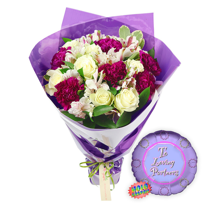 This photograph presents a romantic bouquet and matching balloon against a pristine white background, allowing the colours and shapes to stand vividly in focus. The bouquet is lush and abundant, composed of classic blooms chosen for their romantic symbolism. At its core are creamy white roses, each flower with tightly furled, velvety petals spiralling inward, suggesting elegance, loyalty, and the promise of lasting love. Interspersed throughout are clusters of rich magenta and burgundy carnations, their layered, ruffled petals forming rounded, textured blooms that add depth and an air of passionate intensity. Between these, slender stems of white alstroemeria rise, their delicate, trumpet-shaped flowers revealing inner petals adorned with fine reddish-brown streaks and speckles, lending intricate patterning and visual interest, much like the thoughtful designs created daily by Brent Cross Flowers.   

Surrounding the blossoms is a generous ring of greenery. Smooth, deep-green leaves sit alongside lighter, subtly variegated foliage, providing contrast and reinforcing the feeling of freshness, as if the bouquet were destined for same-day delivery to a nearby home in Brent Cross. The florals are wrapped in two coordinating layers: an inner layer of smooth white paper supports the stems and appears as a sharp, clean diagonal accent, while an outer layer of translucent purple cellophane envelopes the flowers, its crinkled surface catching and softening the light. This purple film rises above the heads of the blooms, framing them with a luminous violet halo that enhances the romantic colour palette. At the base, the stems are tightly gathered and tied with a slim bright green satin ribbon fashioned into a neat bow, from which a light-brown rectangular gift tag hangs, ready for a handwritten note. To the right of the bouquet, placed on the white surface, lies a small, round metallic purple foil balloon with a scalloped border, reminiscent of a rosette or medal. Its lighter lavender centre displays the words To Loving Partners in elegant pink script, complemented by a rainbow-hued holographic sticker, together forming an ideal gift set for anniversaries, proposals, or intimate celebrations across Brent Cross.