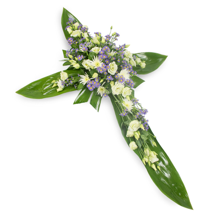 In this serene cross, each botanical choice and placement speaks to remembrance; photographed from a slightly elevated viewpoint on a plain white background, the image invites quiet reflection. The cross's backbone is a carefully layered bed of large, verdant tropical leaves, their slick, green surfaces catching soft, even light that highlights graceful veins and a protective, wing-like curvature. At the intersection and along the arms, clusters of creamy-white and ivory lisianthus unfurl in tender rosettes, their ruffled edges conveying purity and gentle dignity. Interspersed among them are small, rounded white chrysanthemum-type blooms that add a steady, luminous texture, while sprays of tiny lavender or pale purple limonium or aster-like flowers introduce a delicate, consoling hint of colour and a sense of depth. Subtle green fillers are woven through the clusters, giving a natural, mossy softness against the bold structural leaves and producing a pleasing tactile contrast between the waxy foliage and the featherlight petals. The lighting is soft and neutral, bathing the composition in a calm radiance that emphasizes the pale palette and the symbolic cross silhouette. This arrangement carries the language of sympathy and spiritual solace, intended for funerals, memorial gatherings, or church displays, conveying respect, hope, and enduring affection. It sits comfortably within local remembrance traditions around Brent Cross, near Cricklewood Broadway and Hendon Lane, offering families a dignified floral expression for graveside or service use and for inclusion in bereavement guidance or memorial floristry discussions.