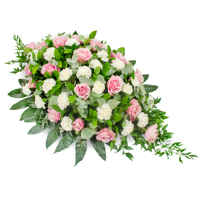 This large, thoughtfully crafted casket spray is captured against a bright white backdrop, allowing every petal and leaf to stand out with clarity. The overall shape is that of an elongated teardrop, widest and most rounded at the head, then gradually narrowing to a graceful point, typical of classic funeral tributes delivered across Brent Cross and the surrounding North West London neighbourhoods. The main feature is a generous array of pink roses, their petals layered in fine, velvet-like spirals that range from delicate blush tones to deeper rose pinks. Some blooms are fully open, revealing their intricate centres, while others remain partially closed, adding a sense of gentle progression and life. interwoven among the roses, white carnations and spray carnations form clusters of soft, cloud-like ruffles, brightening the arrangement and offering subtle texture. The flowers sit in a lush bed of greenery that anchors the design: broad, glossy dark green foliage forms a strong base and frames the edges, while rounded, silvery-green eucalyptus leaves weave through the centre, lending a graceful softness and a slightly cooler tone. From the tapered end and along portions of the sides, slender trails of dark green ruscus extend, giving the piece a natural, cascading finish that suggests a single falling tear or a gentle bow. The mood is calm, reverent, and lovingly composed, ideal for honouring a cherished life at a chapel or cemetery near Brent Cross Shopping Centre or along the Edgware Road. It feels like a tribute arranged by experienced local florists at Brent Cross Flowers, who understand how colour, texture, and shape come together to speak when words are difficult.