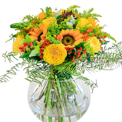 In this sunlit bouquet, Brent Cross's dynamic spirit is reflected through every cheerful bloom. At its heart are radiant sunflowers, their golden faces open wide as though basking on a warm afternoon in the gardens behind Tilling Road. Ensconced around them are yellow roses, tightly layered in velvety spirals, their buttery colour adding richness and softness to the arrangement. The ensemble is peppered with brilliant red hypericum berries, like joyful confetti scattered throughout, capturing both the melody and warmth of a family picnic in nearby Brent Cross Park. Wispy fern fronds and golden fillers spill gently outward, blending with slender green spikes for motion and depth that mimic the verdant hedgerows bordering local walking paths. Dustings of blue-green eucalyptus bring a subtle aromatic freshness and a touch of visual coolness to the mix. The transparent, round glass vase showcases the neatly gathered stems, elevated by the refracted light of clear water. Breathing in the bouquet, there are hints of rose, greenery, and the earthy comfort of fresh-cut stems, making it a welcoming presence on any Brent Cross kitchen table. This arrangement radiates togetherness and light, ideally suited for birthdays, congratulations, or simply sending a vibrant message of joy throughout NW4.