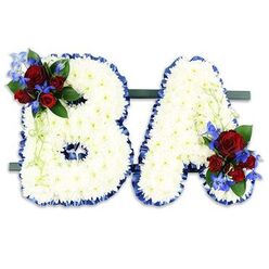 This bespoke sympathy tribute, crafted by Brent Cross Flowers for families in Brent Cross, presents the initials BA in bold capital form, each letter lovingly constructed from a dense carpet of pristine white chrysanthemums. The chrysanthemums create a soft, tactile surface that nearly seems to glow under soft studio light, their tiny petals layered to form a serene, cloud-like field. Each letter's silhouette is sharply defined by a ruffled royal blue satin ribbon, the rich blue providing a clear, respectful boundary that heightens the white's purity. An accent cluster decorates the upper left arc of the B: several deep red roses at various stages of opening, small electric-blue delphinium-like spikes, and slender pale-green trailing foliage that adds movement and a whisper of scent. A matching cluster sits on the lower right of the A, repeating the palette of crimson and cobalt against dark green leaves, producing a thoughtful balance across the pair. The initials are mounted side-by-side on a slim dark green base for stable, freestanding display - practical for a chapel, crematorium or church service near Brent Cross Shopping Centre or Golders Green Crematorium. The arrangement's textures, tones and subtle fragrances-soft chrysanthemum freshness and the rose's quiet perfume-are meant to comfort, to mark a life with dignity, and to offer a tangible emblem of remembrance for loved ones to gather around.