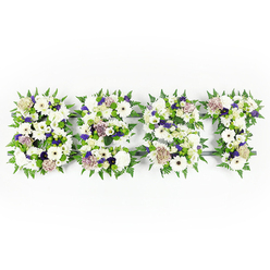 An intimate, hand-crafted floral tribute that spells DAD in large, elegant letters, arranged flat on a clean white background so every texture and tone reads clearly. Each letter is a tapestry of soft whites and dusky purples: velvety ivory gerberas and full white chrysanthemums anchor the design, while pastel coffee-coloured roses and blush-toned spray roses introduce a muted warmth. Ruffled white carnations and delicate lisianthus add cushiony layers, and clusters of violet statice or small purple fillers give a quiet, playful rhythm to the surface. The perimeter of each letter is closely lined with bright green fern fronds, their serrated edges creating a living frame that lifts the petals and clarifies the shapes. Scattered among the blooms are small green button chrysanthemums that bring a pop of fresh verdant texture, and the dark grey structural base peeks through in places, offering a subtle contrast that helps the letters read at a distance. This piece evokes a gentle, consoling scent of mixed florals and green foliage, something you might notice as it leaves the workshop on Hendon Lane on its way to a funeral service. Crafted with the care of a local florist, this arrangement serves as a heartfelt, personalised farewell for a father - a visual embrace that communicates love, respect and remembrance to family and friends gathered to say goodbye in and around Brent Cross and nearby Church End.