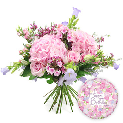 This image captures a beautifully balanced birthday bouquet and balloon ensemble, styled against a clean white background that allows every detail to stand out clearly, as if viewed through the bright windows of a Brent Cross apartment. The hand-tied bouquet is full and rounded, dominated by several large, pillowy hydrangea heads in delicate blush pink. Their tightly clustered petals create a soft, cloud-like mass that gives the design a gentle, romantic foundation. Nestled within and around these hydrangeas are classic pink roses, some already fully open with their spiralling centres revealed, others still partially closed, suggesting a gift that will continue to evolve over the days after it's delivered by Brent Cross Flowers. Threaded between the larger blossoms, tiny clusters of vivid magenta or fuchsia waxflowers, or similar minuscule flowers, add glimmers of deeper colour and a feathery texture, like confetti scattered through a garden. Rising slightly above and weaving through the main blooms are slender campanula stems, their bell-shaped flowers in soft lavender and periwinkle tones adding height and a calming coolness to the arrangement. A generous mix of greenery - fine, lance-like leaves and broader, darker foliage - frames the flowers, giving the bouquet a natural, slightly untamed elegance that would suit both a modern flat near Brent Cross Shopping Centre and a traditional family home nearby. The stems are neatly gathered and visible at the base, showing the careful hand-tied craftsmanship. To the lower right of the bouquet sits a round foil balloon, gleaming softly and covered in a delicate pattern of small roses and floral motifs in coordinating pinks and purples. At its centre, the message "Happy Birthday" is written in graceful purple script, making it instantly clear that this is a thoughtfully curated birthday gift ready to brighten a celebration in Brent Cross.