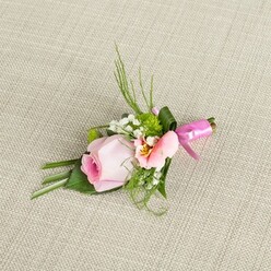 Crafted in the heart of Brent Cross, this exquisite buttonhole arrangement is an ode to gentle beginnings, much like the blossom-laden paths of Brent Park in early spring. The primary bloom, a pastel pink rose, is carefully spiralled at the centre, its core rich and flushed, radiating outward to paler tones evocative of sunrise skies above North London. Flanking it is a soft alstroemeria blossom in lighter peach and blush hues, petals opening shyly to reveal flecks of yellow and hints of delicate striping-details that echo the intricate, hand-tended gardens found along Claremont Road. Tiny stars of white baby's breath swirl across the arrangement, joined by round tufts of vibrant green button mums lending freshness and contemporary flair. The selection of foliage-sleek green blades, feathery ferns, and bold, broad leaves-lends both movement and poise, reflecting the natural elegance curated by the expert team at Brent Cross Flowers. At the base, a shining fuchsia pink satin ribbon gathers the stems, tied into a neat bow that dances with the light, adding a flourish of festive colour and craftsmanship. Resting on a richly textured linen in warm neutral hues, this boutonniere is illuminated by a gentle, ambient glow that enhances every tactile detail, making it a perfect accessory for weddings, proms, and important milestones within the Brent Cross community-where care, beauty, and heartfelt celebration meet.