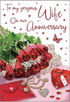 This romantic anniversary composition resembles a cherished still life arranged on a side table in Brent Cross, perhaps just after a special dinner. At its centre, a compact bouquet of crimson red roses sits proudly, each flower lush and fully formed, with petals curling inward in rich, velvety layers. The bouquet is accented with sprigs of fresh greenery that arc delicately outward, giving the arrangement air and a sense of organic grace. Nestled beside the flowers are an envelope and a co-ordinating greeting card, their creamy surfaces bathed in soft light, hinting at handwritten sentiments within. Nearby, a small heart-shaped keepsake box and a gleam of fine jewellery add quiet luxury, suggesting a treasured gift presented to mark the passing years. Tiny red hearts and jewel-like decorations are scattered across the base of the scene, mirroring the roses' passion and creating a sense of celebration without overwhelming the eye. A single butterfly motif appears among them, an almost whimsical symbol of renewed love and new chapters. The lighting is gentle and diffused, casting subtle shadows and making the reds glow richly against the softer background tones. You can almost imagine the faint perfume of the roses mingling with the rustle of card as it is opened. The look and feel echo the thoughtful touches seen in hand-prepared bouquets from Brent Cross Flowers, created for delivery across local homes and apartments. Altogether, the visual story speaks of devotion, shared memories, and the quiet joy of honouring another year together in Brent Cross.