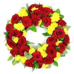 A graceful funeral wreath, perfectly circular and densely flowered, is set against a stark white background that makes its colours appear both vivid and serene. The ring itself is packed with blooms, leaving no visible gaps, symbolising continuity and unbroken memory. Deep red roses dominate the design, each bloom fully open with layered, velvety petals curling gently outward in a natural spiral. The reds range from classic, true red to deeper, wine-tinged shades near the petal edges, adding a sense of depth and subtle movement. Nestled among these roses are generous bunches of bright yellow chrysanthemums, their many narrow petals forming small, cushion-like domes. The warm yellow tones bring a touch of gentle optimism to the wreath, softening the gravity of the red and suggesting comfort and support, much like the quiet green spaces dotted around Brent Cross where families gather after services. Supporting this interplay of colours is a bed of fresh greenery: broad, deep green leaves provide stability and fullness, their slightly glossy surfaces reflecting the soft studio light. Interwoven with these are sprigs of softer, more muted foliage that appear a silvery green, reminiscent of eucalyptus or similar textured greens, which add a cool contrast and delicate detail along the wreath's outer edge. The plain white background and even, diffused lighting ensure that the viewer's attention rests solely on the circle of flowers, highlighting the craftsmanship and care in every placement. The overall impression is of a considered, heartfelt tribute that would be fitting for a funeral, cremation, or memorial service in and around Brent Cross, conveying respect, affection, and a lasting farewell.