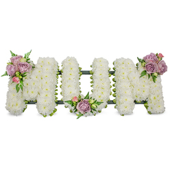 A carefully sculpted sympathy tribute spells out MUM in large, dignified capitals, each letter densely cloaked in pristine white spray chrysanthemums that create a soft, cloud-like surface and a serene visual purity. The arrangement is photographed against a brilliant white background so the texture of thousands of tiny petals is immediately visible: crisp edges, subtle shadowing between blooms, and a tactile, almost feathery quality. Three delicate clusters of accent roses break the white in quiet, deliberate moments - one gracing the upper left arm of the first M, one settling in the inner curve of the U, and a final cluster placed on the upper right arm of the last M. These accents, a mix of muted lavender and pale pink roses in varying stages of bloom, lend a gentle colour echo and a mellow, familiar rose scent that calms the eye. Fresh green foliage, including fine fern fronds and lighter green leaves, is woven through the clusters to add contrast and visual breath. Beneath the flowers a dark green support - ribbon-wrapped wire or moss-lined frame - is subtly visible and defines the letters' shape without drawing attention from the flowers themselves. This composition reads as a tender, private tribute meant for a funeral service or wake, capturing respect, memory, and consolation. Sourced and crafted with care for families across Brent Cross, Cricklewood and nearby Golders Green, it reflects a local florist's commitment to thoughtful, handcrafted sympathy work.