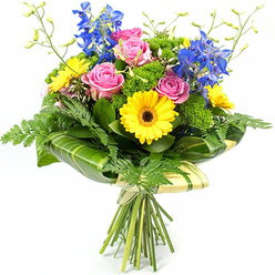 Set against a clean white background that highlights every tone and shape, this vibrant bouquet looks as though it has just been finished on the worktable at Brent Cross Flowers. At the centre sit several pink roses, their petals unfolding in delicate spirals, each bloom slightly different in shape, capturing that natural, romantic softness that appeals for anniversaries or heartfelt thank-yous. Around them, bold yellow gerbera daisies with deep, dark centres spread wide, their layered petals giving off a sunlit brightness that feels as welcoming as stepping into a warm café near Brent Cross station. Tall, elegant stems of deep blue delphinium rise among the central flowers, their clusters of small florets creating vertical lines of cool blue that add drama, structure, and a touch of sophistication. An abundant mix of greenery weaves through and around the flowers: feathery fern fronds peek from the lower edges, softening the outline, while broad, glossy green leaves wrap around the base of the flower heads to form a neat leafy collar, some subtly striped in paler green for extra visual interest. Between these larger shapes, bright green, textured filler foliage builds up the volume, giving the bouquet a rich, full appearance without feeling heavy. Fine, pale green stems tipped with unopened buds extend lightly above the main flowers, suggesting fresh growth and adding an airy, playful rhythm to the composition. The natural stems are gathered and bound with a simple, natural tie, left visible to emphasise the hand-tied craftsmanship. Together, the colours and textures create a joyful, contemporary bouquet - a perfect choice for same-day delivery across Brent Cross when you want to send a message of celebration, encouragement, or simple everyday happiness.