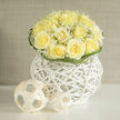 This bouquet is a soft symphony in ivory and pastel: creamy yellow roses gathered into a precise dome, embraced by delicate wisps of gypsophila that dance lightly between petals and give the arrangement a breathy, ethereal quality. The cluster rests on a striking white wicker orb-an almost sculptural element whose open weave introduces tactile intrigue and a modern silhouette beneath the garden-soft blooms. Natural light bathes the scene, drawing a fine sheen across petal edges and tracing the tiny, star-like flowers of the baby's breath, while subtle shadows from the woven sphere add depth and a sense of quiet architecture. Small, minimalist woven spheres placed nearby contribute a playful, contemporary accent, echoing the basket's geometry and suggesting an artful still life rather than a simple vase.

The overall scent is fresh and clean, mingling classic rose perfume with a soft, grassy note that suggests freshly cut fields on a warm morning. As a bouquet often chosen for hopeful moments-new jobs, anniversaries, or a thoughtful congratulation-it feels both comforting and uplifting. Locally minded florists in Brent Cross and surrounding streets from Cricklewood to Colindale frequently recommend this style for airy townhouse interiors or for adding a refined touch to bridal showers held near Brent Cross Shopping Centre. Brent Cross Flowers prepares arrangements like this with attention to balance and longevity, and it's well suited for same-day delivery across the area when a calm, elegant presence is required.