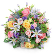 Centered on a clean white background, this lush domed bouquet showcases an artful mix of colours and textures that feels both luxurious and inviting, perfectly suited to the elegant homes around Brent Cross and nearby Finchley Road. The arrangement is densely constructed, forming a smooth, rounded silhouette where every flower appears thoughtfully placed. Soft pastel garden roses dominate in blush pink, warm yellow, and gentle peach tones, their velvety petals unfolding in layered spirals. Some roses are fully open, revealing intricate centers, while others remain more cupped, hinting at continued blooming. Interlaced with the roses are airy clematis blooms, their long, star-shaped petals in shades of white and pale lavender radiating around bright yellow centers, adding lightness and a graceful, climbing-garden feel. Blue eryngium-sea holly with spiny, metallic-blue heads-stands upright amid the softness, providing cool contrast and a slightly untamed edge. Deep purple lisianthus, from tight buds to softly opening flowers, nestle among the larger blooms, introducing depth and gentle shadow. Scattered throughout the bouquet are clusters of glossy red hypericum berries, their small, round forms catching the light and bringing a playful, jewel-like touch. The entire arrangement is held together by a supportive bed of mixed foliage: broad, glossy green leaves form a steady base, while feathery greens and hints of darker, burgundy-tinged foliage peek through, enriching the visual layers. Soft, even lighting highlights the colours without harshness, and a faint shadow beneath suggests the bouquet's generous volume. The overall mood is joyful yet refined-a versatile design perfect for celebratory deliveries around NW11, expressing congratulations, sympathy, or simple gratitude with natural elegance.