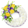 A tender circular tribute in the shape of an 'O', composed of hundreds of small, pristine white spray chrysanthemums densely packed to form a soft, cloud-like ring set against a clean white background. The wreath's texture reads almost like wool - plush, layered petals creating a uniformly luminous surface that speaks of quiet respect and calm. Anchoring the design at the upper left curve is a vivid, asymmetrical spray: several golden-yellow roses, fully unfurled with buttery, spiralled petals that capture a hint of warm sunlight, sit beside clusters of deep royal-purple lisianthus whose ruffled, cup-shaped blooms introduce a velvety coolness. Lighter lavender lisianthus buds and small green shoots punctuate the spray, offering visual depth and the suggestion of gentle movement. Interwoven glossy, rounded leaves, slender fern fronds and variegated foliage lift and separate the colours so the yellow and purple read clearly against the white field. A fine thread of dark purple mesh peeks from beneath the chrysanthemums along the wreath's inner and outer edges, a subtle echo of the lisianthus tones and a refined finishing touch. The open centre preserves the wreath's traditional silhouette, while the overall palette - white for peace, yellow for remembrance, purple for dignity - conveys sympathy without grandiosity. As a local florist might note for mourners in Brent Cross and nearby Cricklewood, this handcrafted sympathy wreath is intended to offer solace, a quiet visual cradle for memories, and an understated message of farewell rendered with delicate workmanship and genuine care.