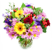 A lush mixed bouquet rises elegantly from a clear glass vase, its colours set off against a crisp white background that emphasises every nuance. At the heart of the arrangement, sumptuous red roses unfold in velvety spirals, their deep colour bringing a touch of timeless romance and depth. Close by, two vivid yellow gerbera daisies with rich brown-orange centres shine like miniature suns, their round, layered petals giving the display a bright, optimistic character that feels right at home in Brent Cross's lively community. Encircling these star blooms, generous clusters of soft pink daisy chrysanthemums add volume and softness, each flower composed of many fine petals gathered around a tiny yellow centre, creating a plush, cushiony halo. Threaded delicately among the daisies and roses, lisianthus flowers in shades of purple and lavender curve and twist, some buds still slightly closed while others open into bell-shaped forms with lightly ruffled edges, adding cool, sophisticated notes. Between petals, rounded red hypericum berries peek out like polished beads, contributing both colour and a pleasing textural contrast. The bouquet is framed by an assortment of greenery - broad, glossy leaves mingling with slender, airy sprigs - giving it movement and a fresh-from-the-florist feel, as though it has just left a Brent Cross workspace near the North Circular to be delivered across nearby neighbourhoods. Within the cylindrical glass vase, the straight, trimmed stems are clearly visible through the clean water, underscoring the careful craft behind the design. The overall impression is one of abundant joy and thoughtful intention, ideal for birthdays, congratulations, or brightening a dining table after a visit to Brent Cross Shopping Centre, adding a warm floral presence to everyday life.
