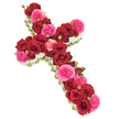 An elegant floral cross designed for a funeral or memorial service appears against a bright, uncluttered white background, its entire surface richly upholstered with roses and small white flowers. The upright and arms of the cross are densely covered with large, fully opened red roses, whose velvety petals in deep crimson shades create a powerful field of colour that speaks of enduring love, strength, and reverence. Interspersed throughout this sea of red are striking fuchsia pink roses, their slightly ruffled, garden-style petals adding a softer glow and an intimate, comforting warmth to the arrangement. Between the open blooms, smaller rosebuds in matching reds and pinks create an appealing texture and a sense of evolving memories, from early days to a well-lived life. The outline of the cross is gently highlighted by a continuous edging of tiny white blossoms-likely spray chrysanthemums or miniature carnations-placed closely together to form a fine, cloud-like border, echoing themes of purity, peace, and spiritual grace. Subtle touches of fresh green foliage and fine leaves peek from beneath the mass of roses, giving the piece underlying structure and a whisper of nature's renewal. The lighting is even and tranquil, allowing every hue and petal texture to be seen clearly without harsh shadows, supporting the overall mood of quiet reflection. This style of floral cross, familiar to many in Brent Cross, Colindale, and the wider North West London community, is often displayed beside the coffin or near the front of the chapel, offering a gentle yet dignified visual expression of condolences, remembrance, and faith during a final farewell.