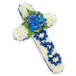 A deeply personal floral cross, created as a tribute to a father, is pictured on a bright white background, its serene colour palette of white and royal blue standing out clearly, much like a design just finished in a Brent Cross flower shop. The full shape of the cross is densely covered with white spray chrysanthemums, each small blossom nestled closely to the next, creating a thick, gently mounded surface that appears soft and comforting to the touch. Encasing this pure white floral base is a carefully applied royal blue satin ribbon, the fabric glossy and smooth as it follows the perimeter of the cross, cleanly defining the shape and giving the design a formal, reverent character. At the centre where the arms meet, a lush focal spray of blue flowers rises: frilled, full-petalled blue carnations combined with slender, graceful blooms reminiscent of blue delphinium or orchids. These are interwoven with deep green fern fronds and leaves that spill slightly outward, offering both contrast and an organic flow that softens the structure. Along the vertical length of the cross, the word DAD is thoughtfully spelled out using narrow loops of the same blue satin ribbon, each letter resting gently on the chrysanthemum cushion and adding a clear, emotional message to the piece. The evenly lit, shadow-soft background ensures that the colours and textures of the flowers and ribbon are the sole focus. The overall effect is peaceful, dignified, and loving-a floral cross that could be delivered across Brent Cross, Hendon, or nearby Barnet for a funeral, wake, or graveside service, expressing heartfelt remembrance when words feel too small.