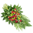 A refined sympathy spray is arranged on a stark white background, its long, tapering shape suggesting a quiet, flowing movement from top left to lower right. At the centre, rich, deep red flowers gather in a dense, emotive cluster: classic roses with velvety petals, some open to reveal their spiralled hearts and others still in tight bud, mingle with red gerbera daisies marked by darker centres and soft, ruffled red carnations. This concentrated crimson heart forms the emotional anchor of the tribute, representing love, honour, and remembrance. Threaded between and around these blooms, bright lime green chrysanthemum pompons create vivid points of contrast, their small, rounded heads bringing a crisp, modern energy to the otherwise traditional palette. Scattered lightly throughout the spray, tiny white filler flowers-similar to gypsophila or miniature daisies-soften the arrangement, adding an airy, almost mist-like layer that lightens the overall effect. Surrounding the flowers, a generous frame of foliage supports and shapes the design: broad, glossy salal leaves supply a dark green foundation, while feathery leatherleaf fern and other greenery contribute both volume and subtle movement. At the lower right tip, long, broad green leaves fan outward in a clean arc, reinforcing the elegant, elongated form. At the upper left, a neat bundle of tall, straight green stems or leaves rises vertically from the spray, encircled at the base by a single broad leaf wrapped with care, imparting a contemporary, architectural note. Crafted in a style often seen at services around Brent Cross and nearby crematoria, this arrangement would sit naturally as a casket spray, a standing tribute, or a central memorial display, offering a calm, dignified farewell.